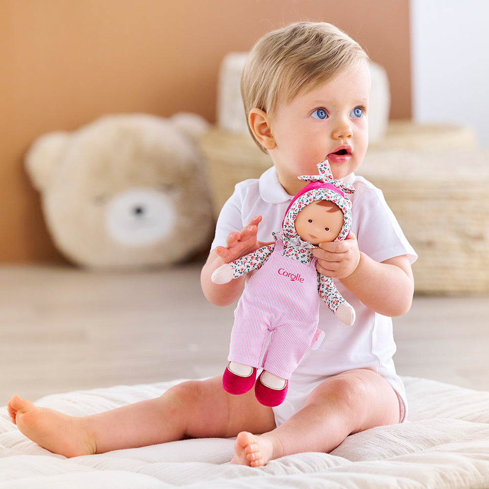 Doudou Corolle Miss Chic rose grenadine, un enfant jouant avec la poupée Corolle de 25 cm.