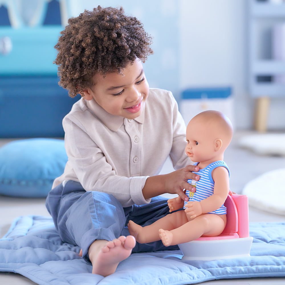 Enfant jouant avec un poupon sur des toilettes interactives poupon, encourageant l'apprentissage de la propreté.