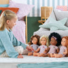 Une fille jouant avec plusieurs poupées corolle 36 cm dans une chambre colorée.