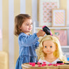 Une petite fille coiffant une poupée avec le coffret coiffure Corolle, jouant avec créativité.