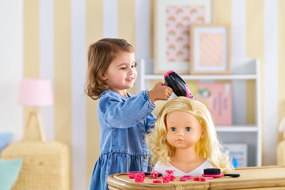 Une petite fille coiffant une poupée avec le coffret coiffure Corolle, jouant avec créativité.