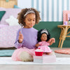 Une fille avec une poupée Corolle en robe de princesse, jouant avec un cupcake et une baguette magique.