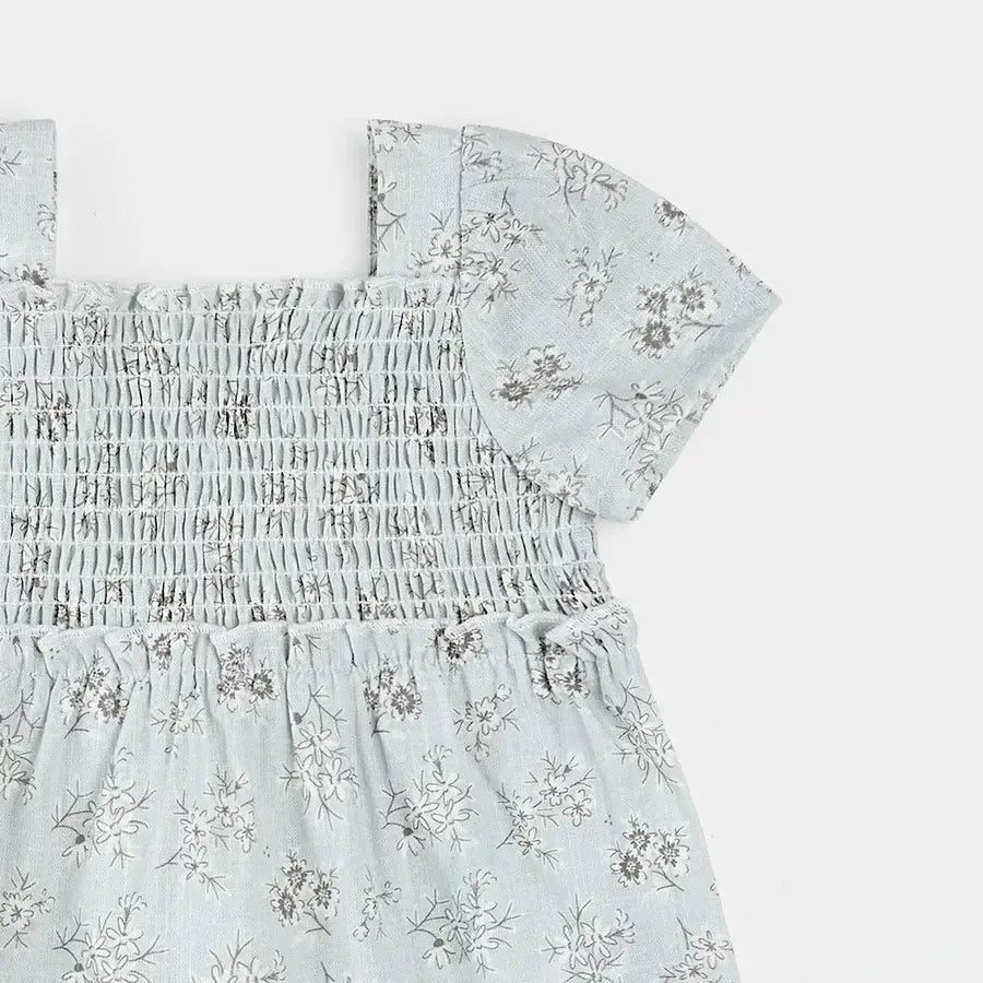Détails de la robe bleu poudré imprimé floral avec haut smocké et jupe à volants.
