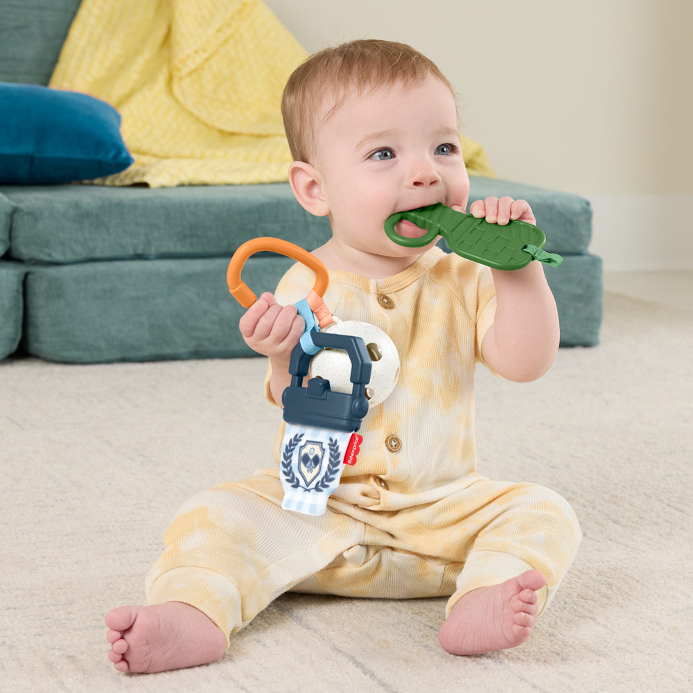 Bébé jouant avec le coffret cadeau pickleball Fisher-Price et des jouets d'éveil colorés.