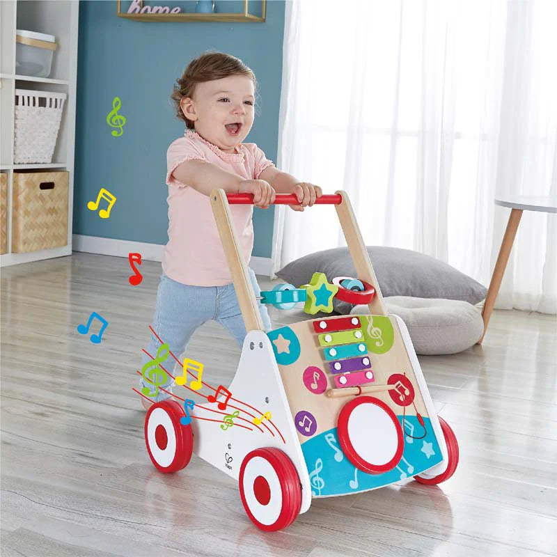 Un bébé heureux utilisant le Hape-Mon 1er trotteur musical pour bébé, entouré de notes de musique.