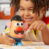 Enfant jouant avec le jouet Monsieur Patate, souriant et créant des visages amusants sur la figurine.