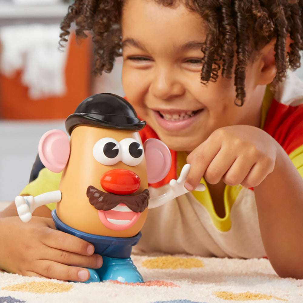 Enfant jouant avec le jouet Monsieur Patate, souriant et créant des visages amusants sur la figurine.