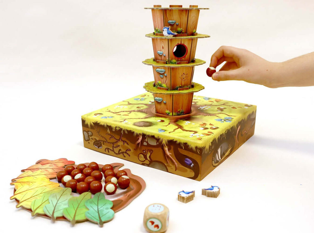 Jeu d'adresse écureuils noisettes, enfant jouant avec des noisettes et des éléments de jeu colorés sur le plateau.