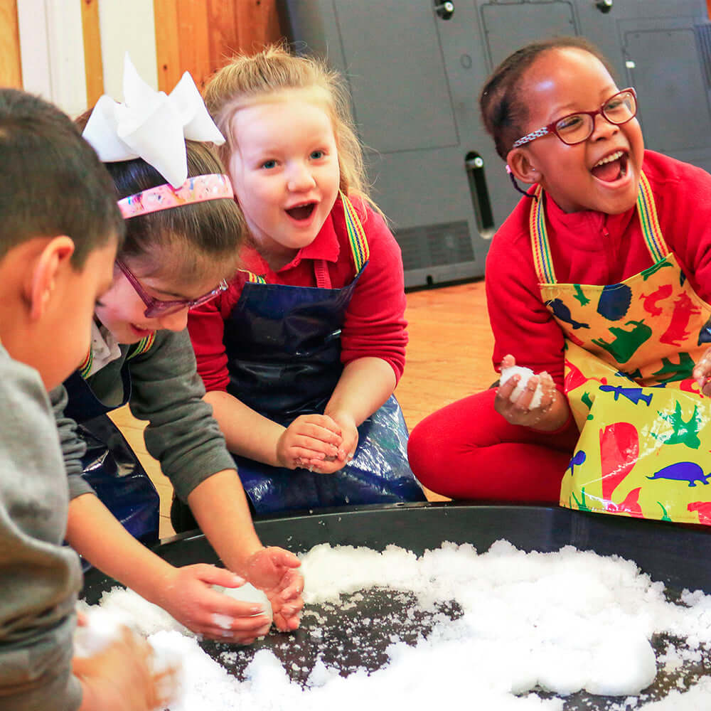 Enfants jouant avec des boules de neige artificielles Zimpli, s'amusant et souriant pendant une activité ludique.