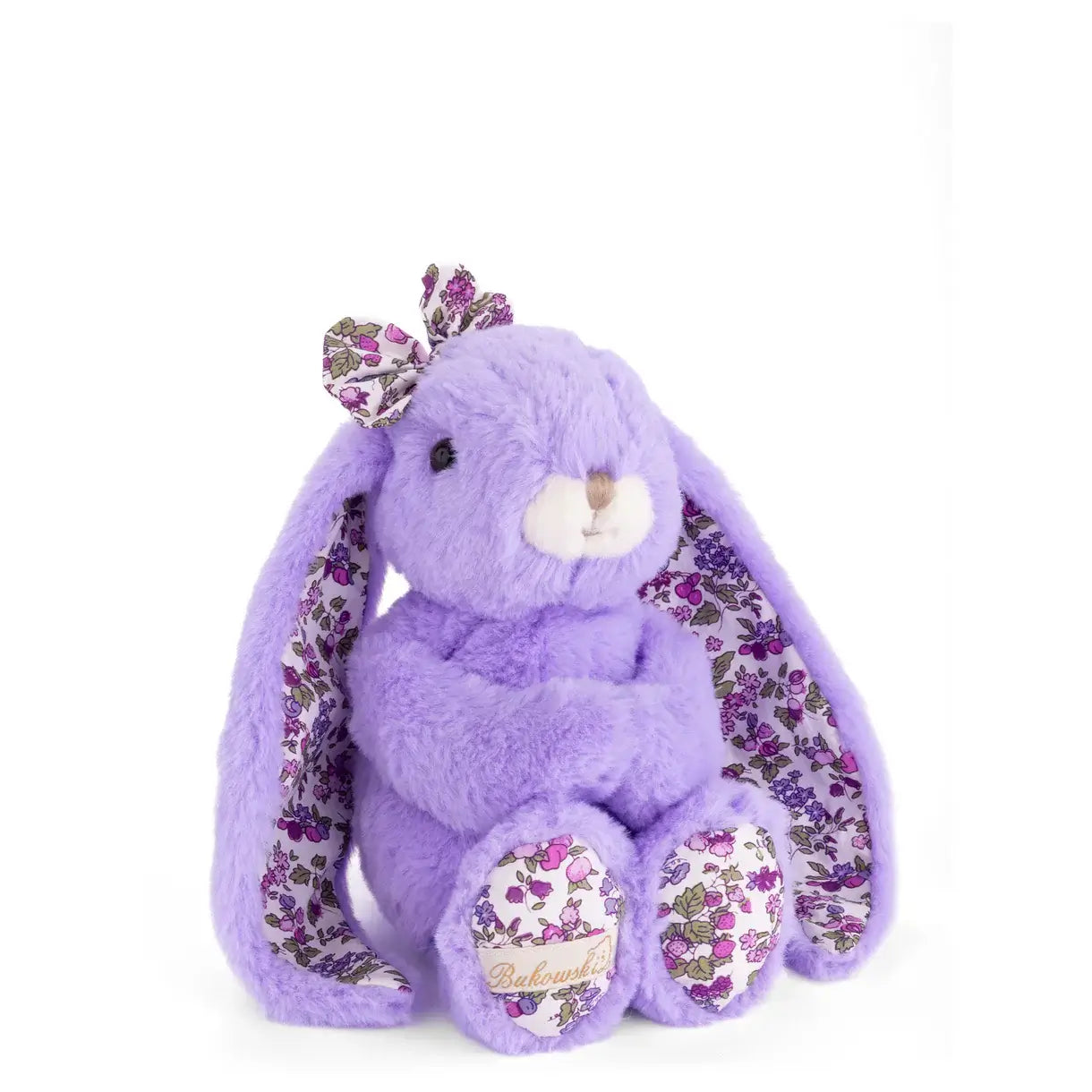 Peluche lapin doux floral de couleur lavande, avec de longues oreilles et un nœud floral sur la tête.