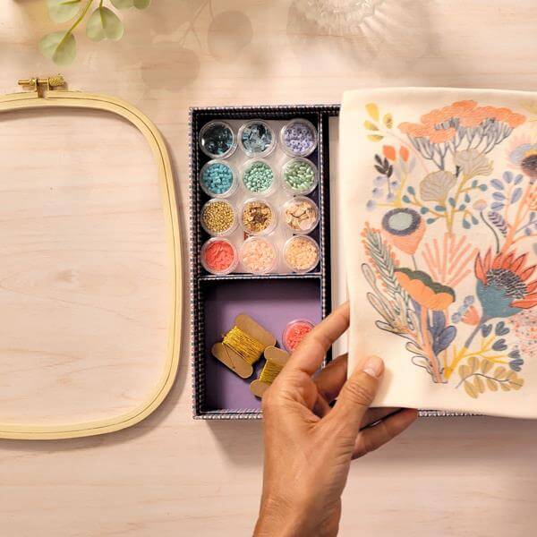 Image d'une main tenant un tissu brodé avec des perles, relevant le savoir-faire du perlage haute couture.
