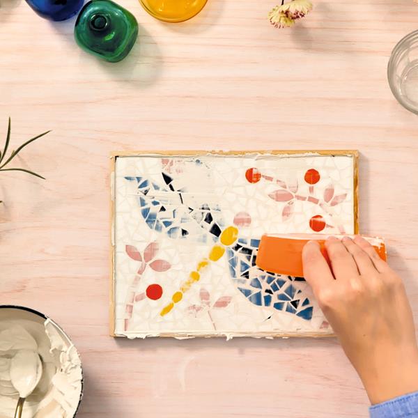 initiation mosaïque libellule : création d'une mosaïque avec des morceaux colorés et un outil de mosaïste.