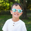 Petit garçon souriant portant des lunettes de soleil Urban Xplorer - Bleu Pale Aurora.
